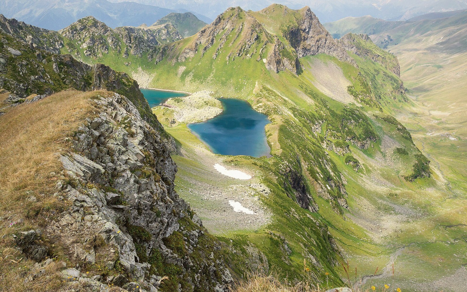 Turquoise alpine lake nestled in a green valley surrounded by rugged mountain peaks